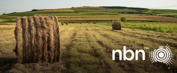 Field in regional Australia with hay bales and power lines in far distance, NBN logo overlay.