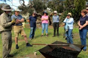 Group of people gathered around a kiln at a biochar workshop