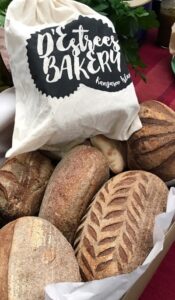 Fresh baked loaves with calico bag branded with D'Estrees Bakery logo.