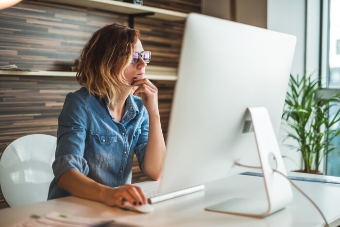 Woman looking thoughtfully at computer monitor.