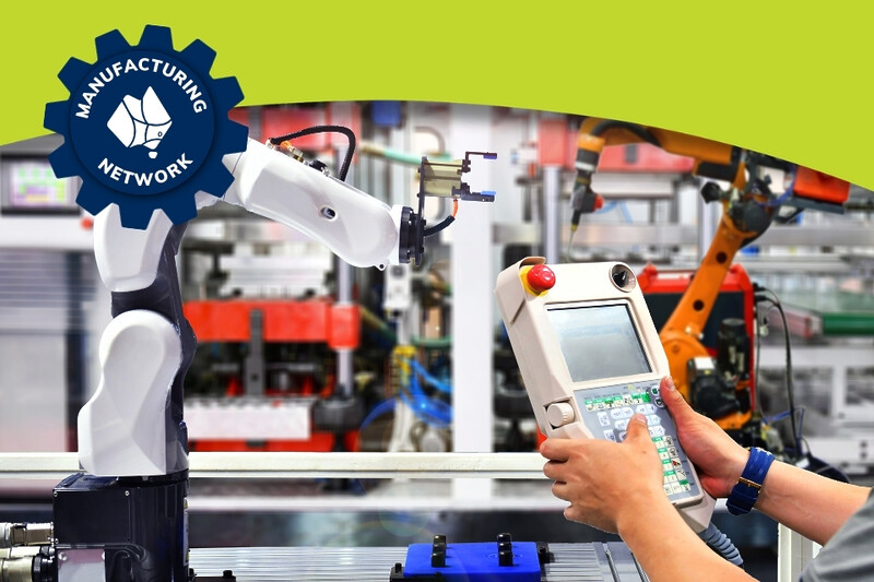 Hands holding a control panel for manufacturing robotics in the background.