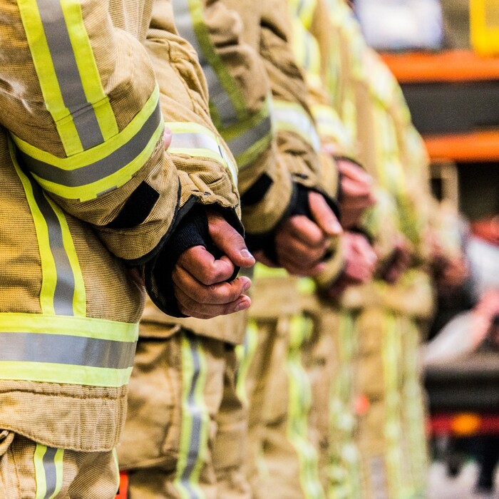 Row of clasped hands belonging to emergency services workers